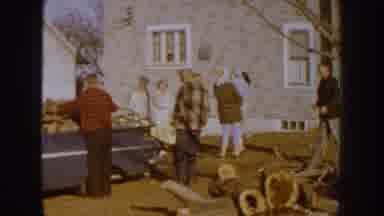 Nebraska USA (1959): Group Of People Standing Near Wood Logs And Blue Vehicle