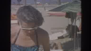 Hawaii USA (1961): Woman Swimsuit Sunglasses Sits Beach Chair Man Walking Sand