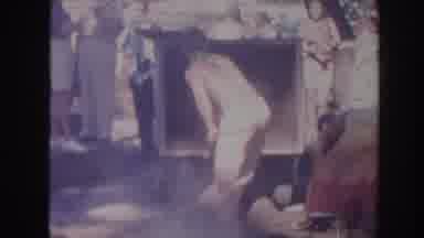Hawaii USA (1961): Men Wearing Colorful Sarongs Shoveling Dirt Into A Smoky Fire