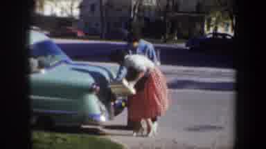 Portland Oregon USA (1957): Woman Wearing Blue Robe Takes Yellow Box To People