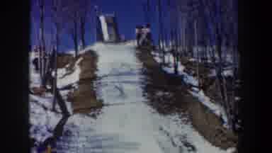 New York USA (1962): People Stand At The Top Of A Snow Jump Under A Blue Sky