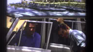 Kenya (1969): Two Smiling People Hanging Out By Vehicle With Doors Open Outside
