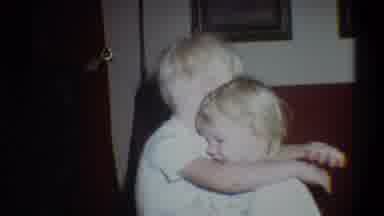 Troy New York USA (1973): Young Blonde Child Hugging Younger Sibling In Living
