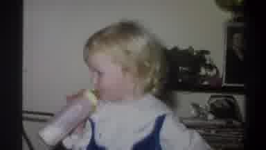 Troy New York USA (1973): A Blonde Toddler Sucks On A Bottle As A Mature Man