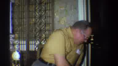 Troy New York USA-1973: Old Man Reaching Over His Chair To Play With His