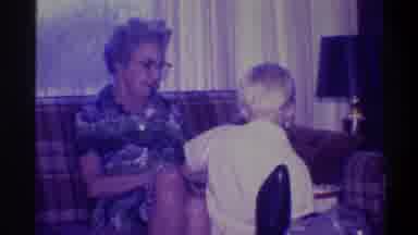 Troy New York USA (1973): Woman Sitting On Sofa And Wearing Glasses Looks At Child
