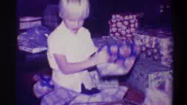 Troy New York USA (1973): A Young Blonde Child Opening A Christmas Present Happily