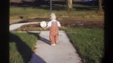 Gainsville Florida USA (1974): A Small Child Walks Around Outdoors Holding An