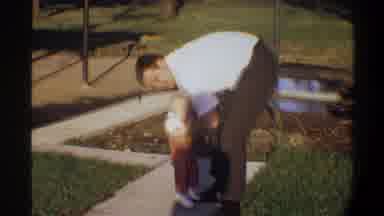 Gainsville Florida USA (1974): A Man Picking Up An Infant Outside