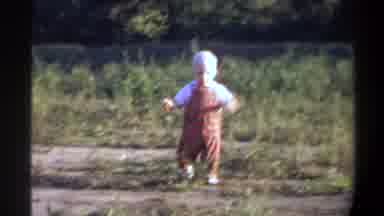 Gainsville Florida USA (1974): Child In Red Suit Walking On Dirt Floor With Some