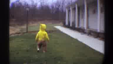 Gainsville Florida USA (1974): Man Wearing Black Suit Watches Baby Wearing Yellow