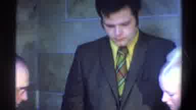 Gainsville Florida USA (1974): Man Wearing Grey Suit Multicolor Tie Watching Baby