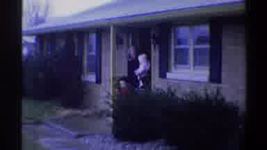 Gainsville Florida USA (1974): Boy Wearing A Black Beanie And Red Suit Walks Out