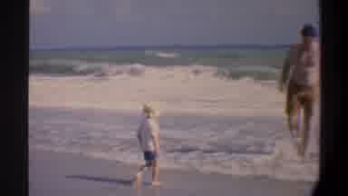 Gainsville Florida USA (1974): Man In Bathing Suit Shows Child With Hat Something