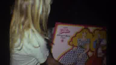 Gainsville Florida USA (1975): A Small Girl Opens Her Gift While Sitting Beside