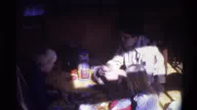 Gainsville Florida USA-1975: Father and Children Gather Around Table in Vintage Home Movie