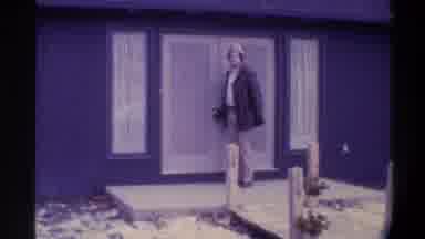 Gainsville Florida USA (1975): Man Dressed For Cold Weather Lets Go Of Door Knob