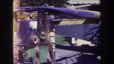 Volmer Yucaipa California USA (1969): A Green Biplane Sits In Front Of A Garage To