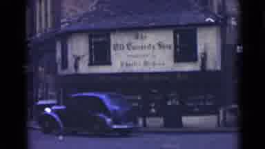London England (1946): Black Vintage Car Around The Corner Of A Two Story