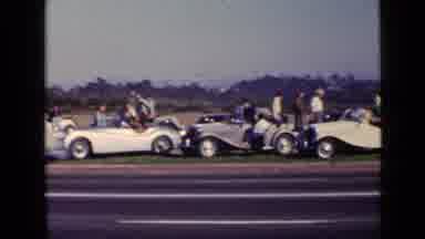 San Diego California USA (1949): People Looking At Classic Cars On The Road As