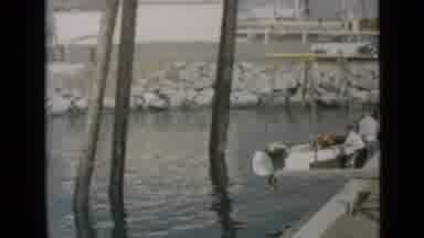 San Diego California USA (1949): Men Placing Blue White Boat Into Water On Clear