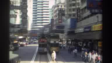 HONG KONG-1982: Traffic Travelling Down An East Asian Street In A Town With An