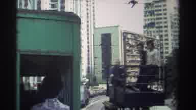 Hong Kong (1982): Three Men In Yellow Construction Vehicle Passes Green Bus On