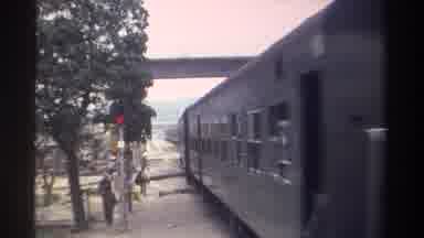 Taiwan (1982): Commuter Train Travels Under An Overpass Passes Pedestrians Near A