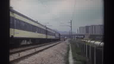 Taiwan (1982): Tan And Black Train Drives Along Train Tracks Alongside City