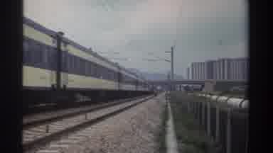 Taiwan (1982): Person Watches Brown Yellow Colored Train Roll By On A Clear Day