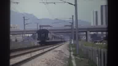 Taiwan (1982): Train Shown Slowly Going Forward Down Tracks Underneath Busy