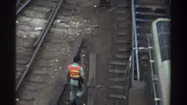 Taiwan (1982): Man Wearing Orange Work Vest Crossing Railway Tracks While Train