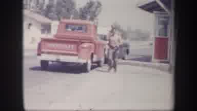 Arizona USA-1957: Man Wearing Red Shirt Running Past Parked Red Truck On Bright