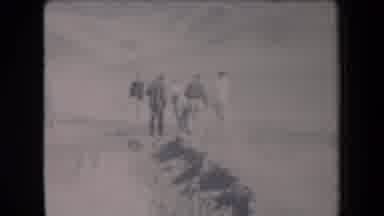 Arizona USA (1958): Men Walking In A Group Through The Desert With Mountains In
