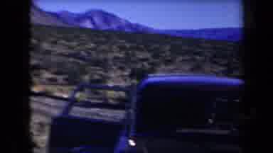 Arizona USA (1958): Three Men Leaning Over A Dark Car At The Base Of Mountains In