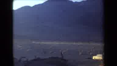 Arizona USA (1958): Yellow Car Parked In Dusty Barren Desert At Base Of Large