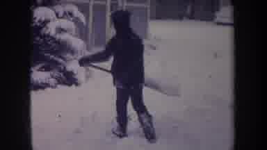 Michigan USA (1968): Boy In Dark Blue Winter Clothes Is Shoveling Snow In Front Of