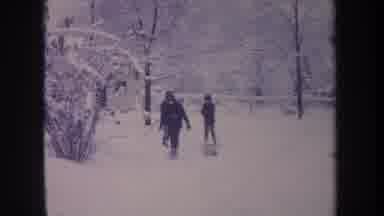 Michigan USA (1968): Three Kids Sledding In The Snow And One Is Kicking Around The