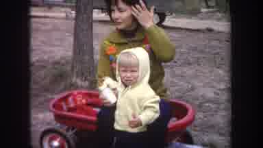 Michigan USA-1968: Family Moment With Child In Red Wagon And Wooden Crib