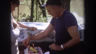 Michigan USA (1968): Man Lights Candles On Racecar Birthday Cake At Outdoor Picnic