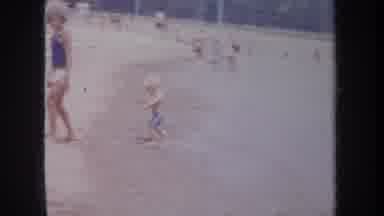 Michigan USA (1968): Boy Wearing Blue Shorts Running From Beach Surf On A Bright