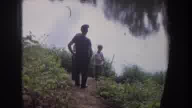 Michigan USA (1968): Man With Two Children Standing On River Bank Surrounded By