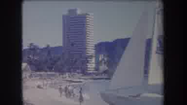 Hawaii USA (1969): People Along The Shore Of A Beach With A Sailboat Docked Along