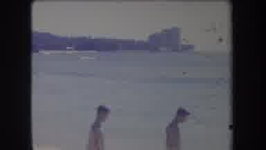 Hawaii USA (1969): Man Wearing Blue Shorts Walking On Beach While Distant Boat