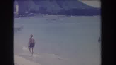 Hawaii USA (1969): Male In Blue Shorts Walks Along Beach Toward Beached Sailboat