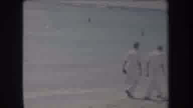 Hawaii USA (1969): Two Men Dressed In White Walking On A Beach With Several People