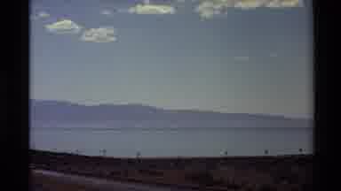 Western USA (1980): Cars Drive Lazily Down Road Nearby To Expansive Ocean Front