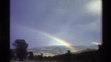 Western USA (1980): A Beautiful Rainbow And A Field In Front Of A Rocky Mountain