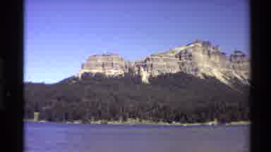 Western USA (1980): Body Of Water With Forest On Shore Followed By Pyres Of Rock