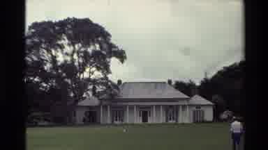 New Zealand (1981): Two Couples Walking To And Past White Colored House On A